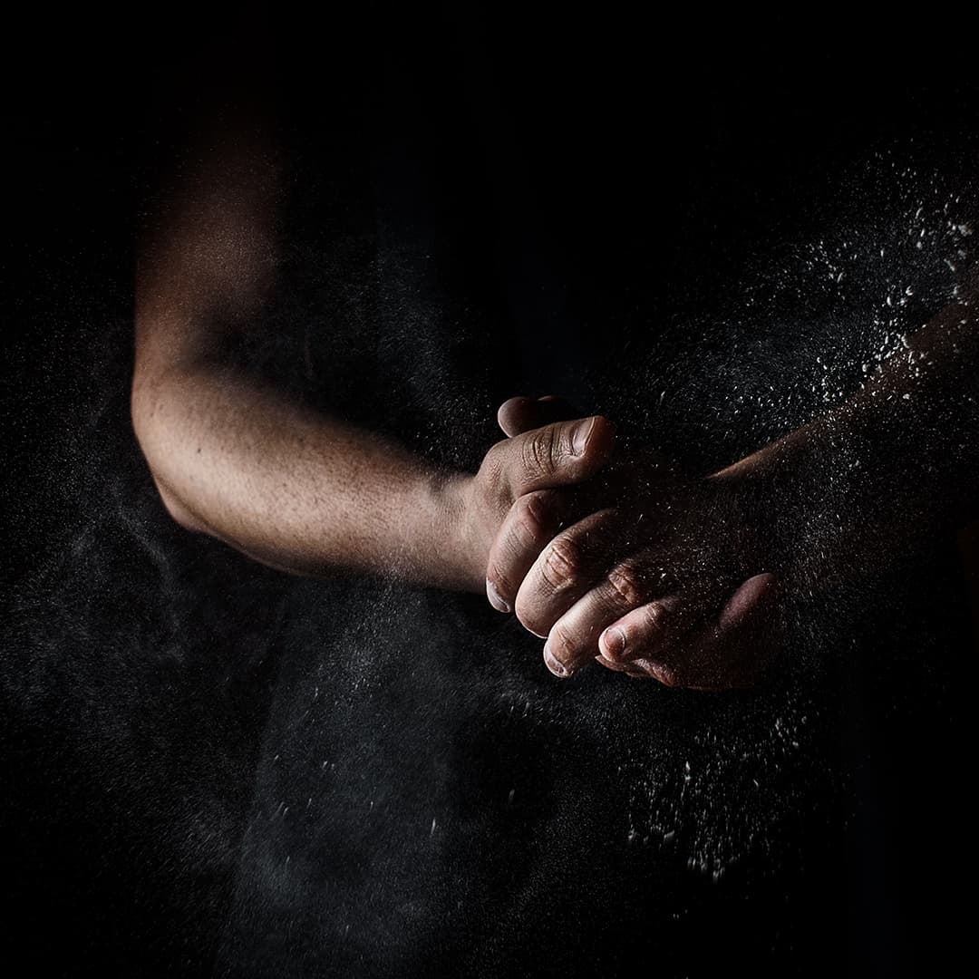 Kaksi kättä tarttuvat toisiinsa tummaa taustaa vasten — sovinto ilman oikeudenkäyntiä.